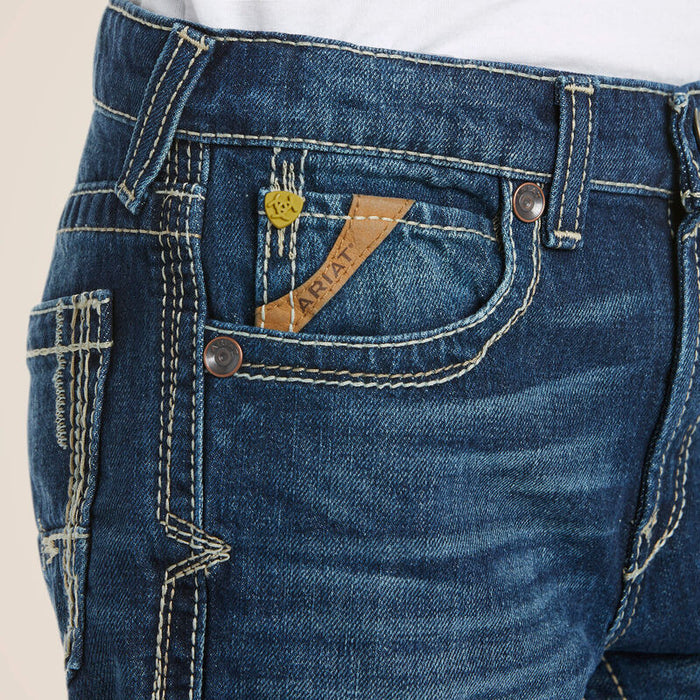 Boy's Ariat B5 Slim Fit jeans in a dark wash. Close up of stitching details and Ariat logo on front pocket.