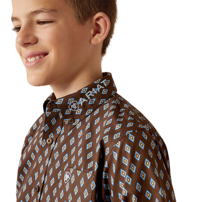 Boy's Ariat long sleeve team logo shirt in brown with a blue diamond pattern. Close up of Ariat logo on button down collar and Ariat shield logo on left chest pocket.