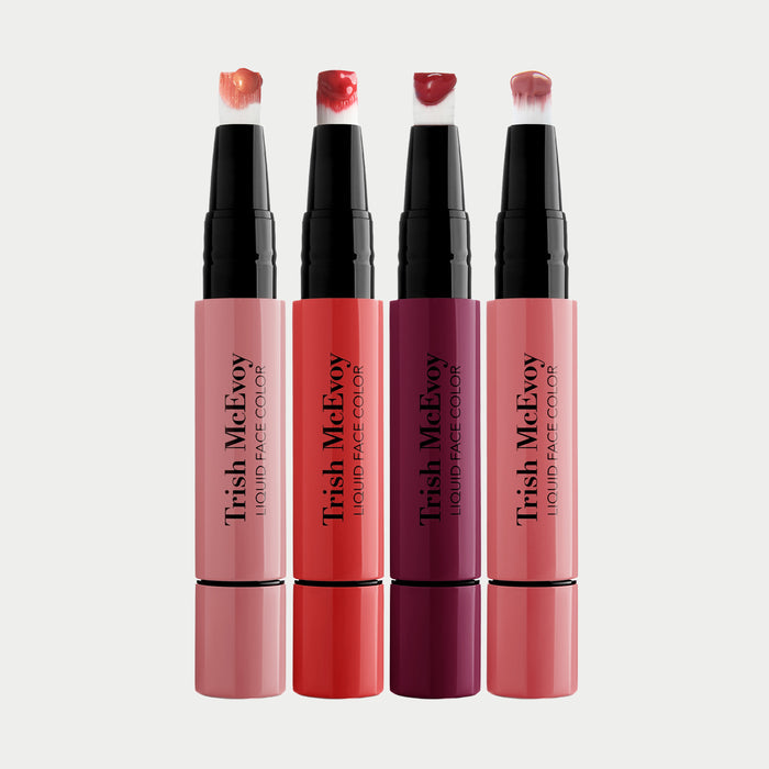 Four Trish McEvoy liquid face colors with visible caps on a light gray background