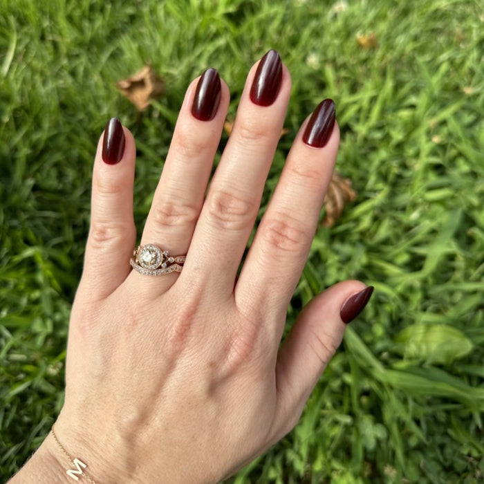 Obsessed - Press-On | Medium | Almond showing hand with dark ruby almond press-on manicure outdoors on grass background