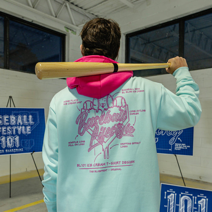 Person wearing a light blue hoodie with pink Ice cream graphics and text, holding a baseball bat.