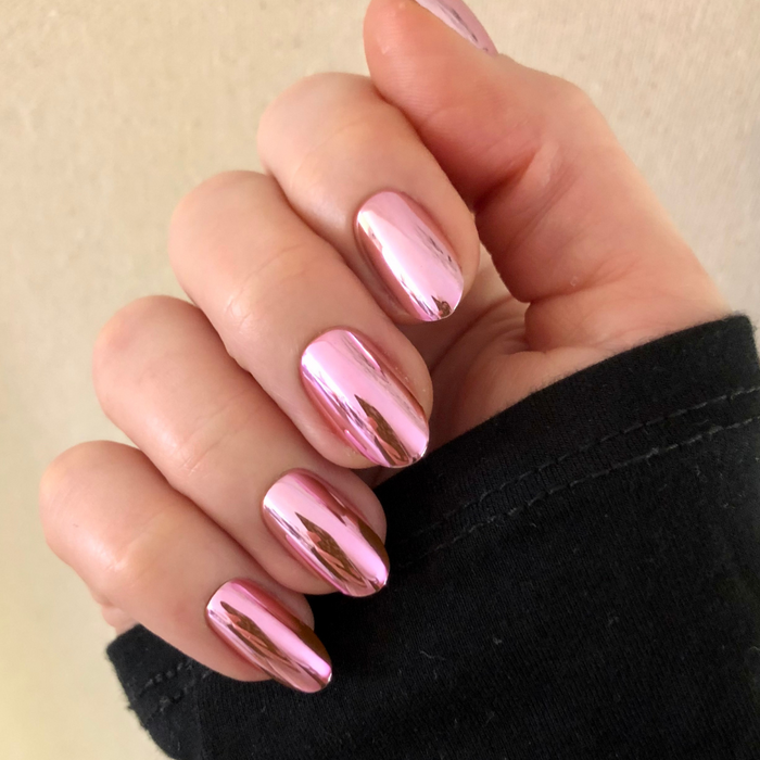 Pink Mirror Chrome - Press-On | Medium | Oval showing a hand with shiny pink chrome medium oval press-on manicure indoors