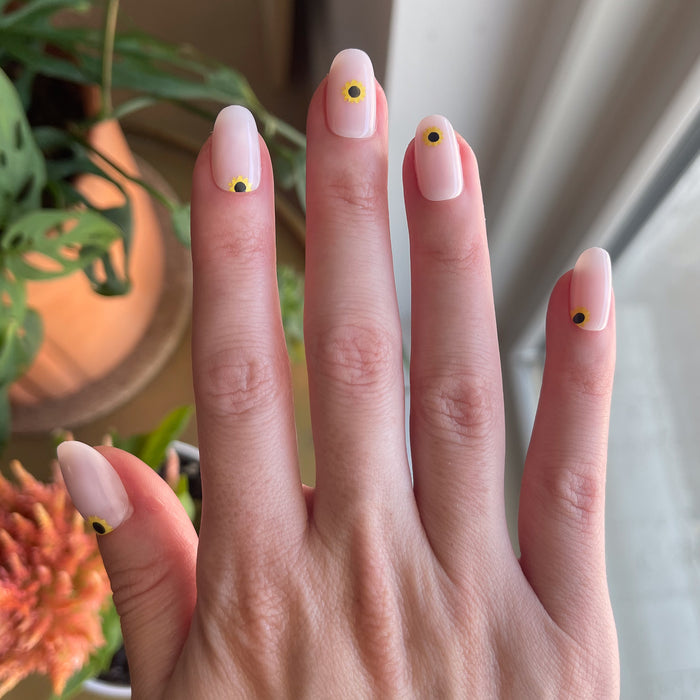 Scattered Sunflower - Press-On | Short | Round featuring short round false nails with single sunflower designs on natural hand indoors