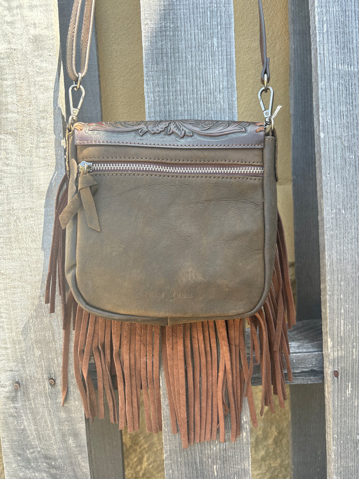This Coffee Brown tooled leather crossbody bag has a turquoise inlay in the flap closure bordered with whip stitch. It has brown fringe, strap, and back. Rear view showing zip closure pocket.