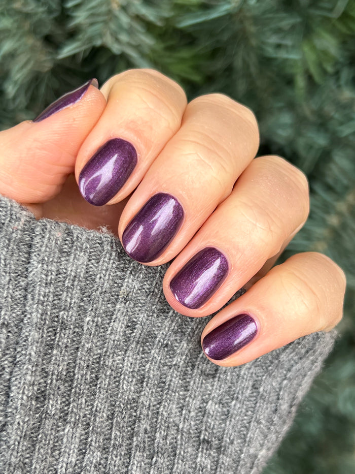Hand with short nails painted in deep purple with golden shimmer using My Favorite Color polish by Olive and June