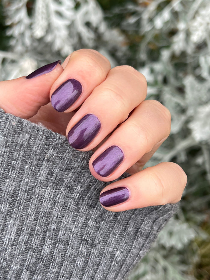 Hand with short nails painted in deep purple with golden shimmer using My Favorite Color polish by Olive and June