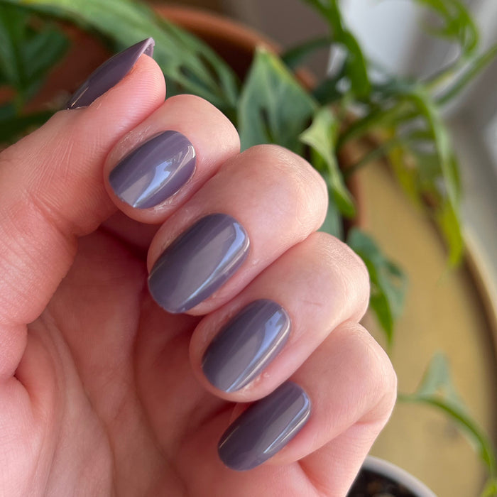 Art Class - Press-On | Short | Round showing hand with glossy muted eggplant purple short round press-on manicure indoors