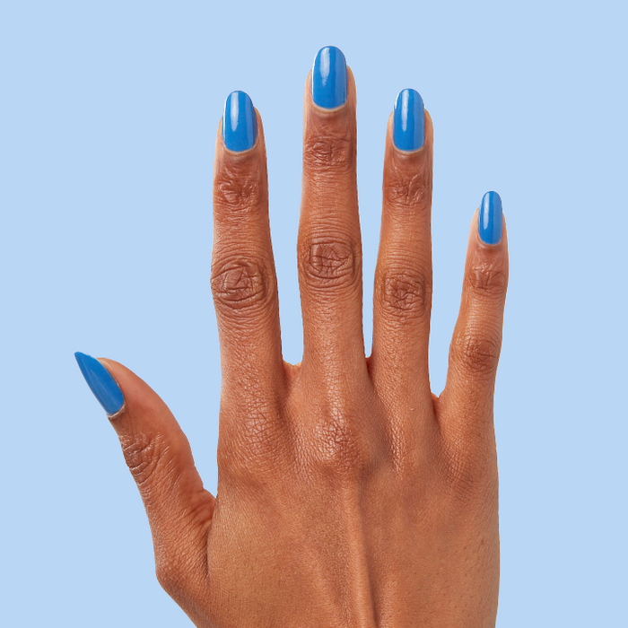 Hand with long, almond-shaped nails painted in Blue Canoe nail polish against a soft blue background