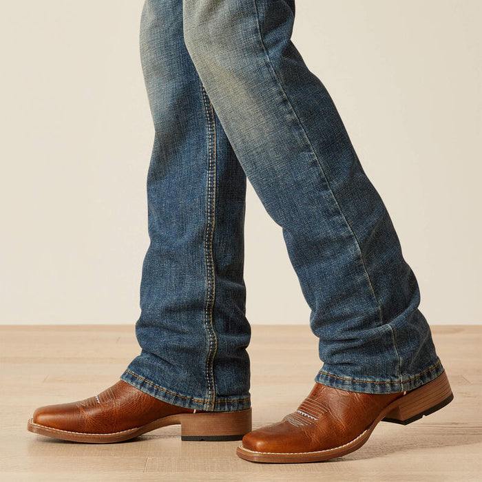 Boy's Ariat relaxed fit boot cut jeans in a medium wash. Bottom view showing leg opening.