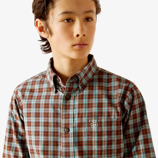 Boy's Ariat long sleeve shirt in Bitter Chocolate Plaid. Close up front view of button down collar and Ariat shield logo on left chest pocket.