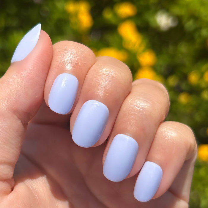 BP - Press-On | Extra Short | Round showing hand with icy light blue extra short round press-on nails outdoors in sunlight