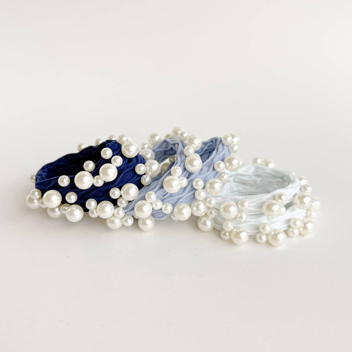 Set of pearl hair ties in blue, white, and gray on a light gray background