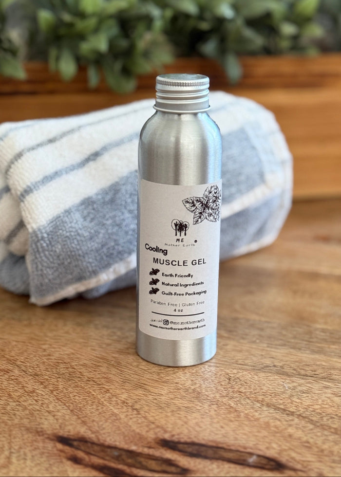 Metallic bottle of muscle gel on a wooden surface with a towel and plant in the background
