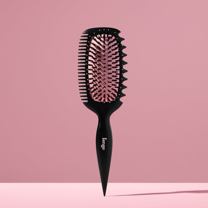L’ange Curl Sculptor brush standing upright against a pink backdrop