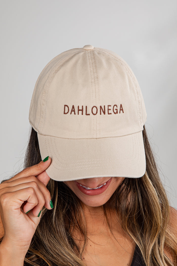 Beige cap with 'DAHLONEGA' text worn by a person against a plain background