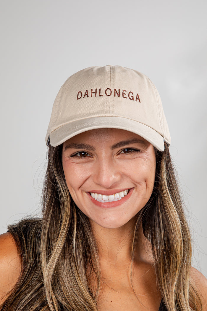Woman wearing a beige cap with 'DAHLONEGA' text on a plain background