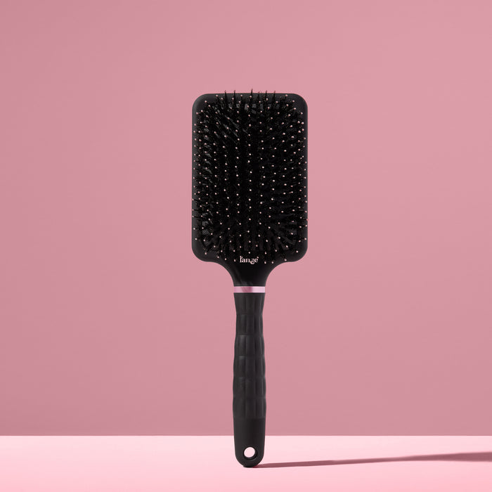 black L’ange detangling paddle brush with nylon bristles and boar standing upright on pink background