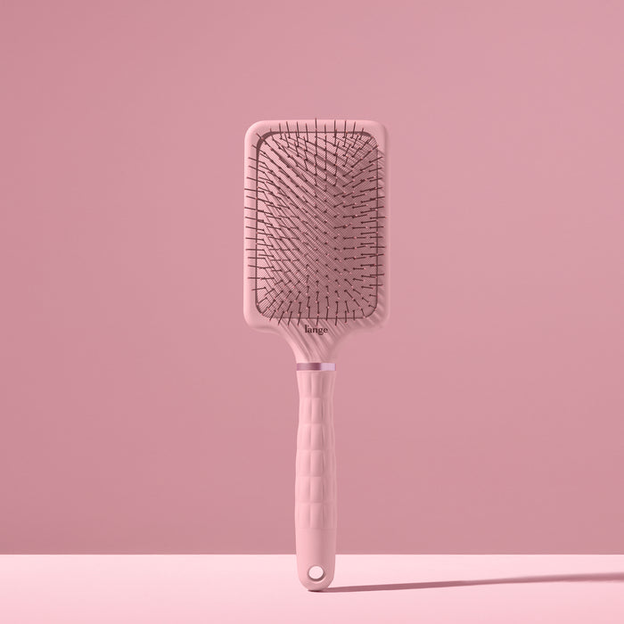blush L’ange detangling paddle brush with nylon bristles standing upright on pink background