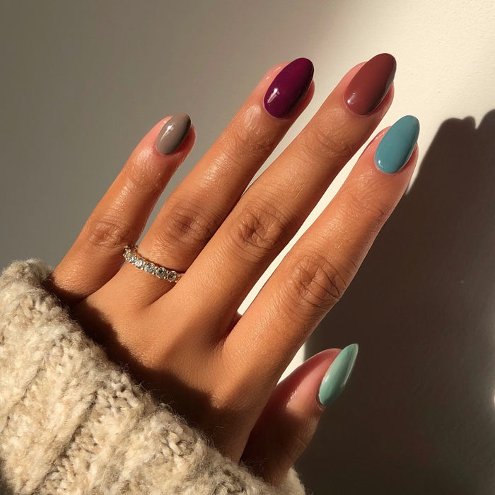 Elite Collection mix-and-match manicure in nude, brick red, plum and teal with a ring in sunlight