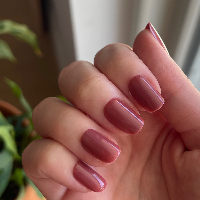 Fig Ranch - Press-On | Short | Squoval showing hand with short squoval cool fig pink press-on manicure indoors near window light