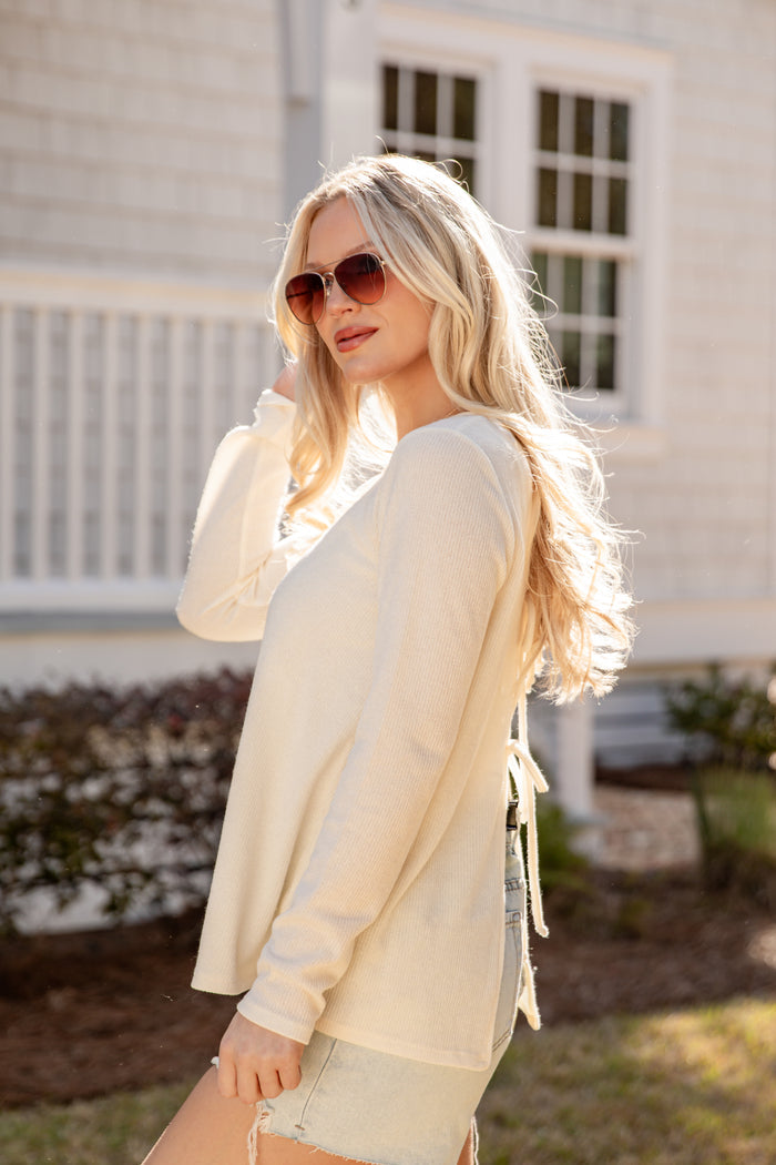 Woman wearing a light-colored cardigan and sunglasses outdoors.