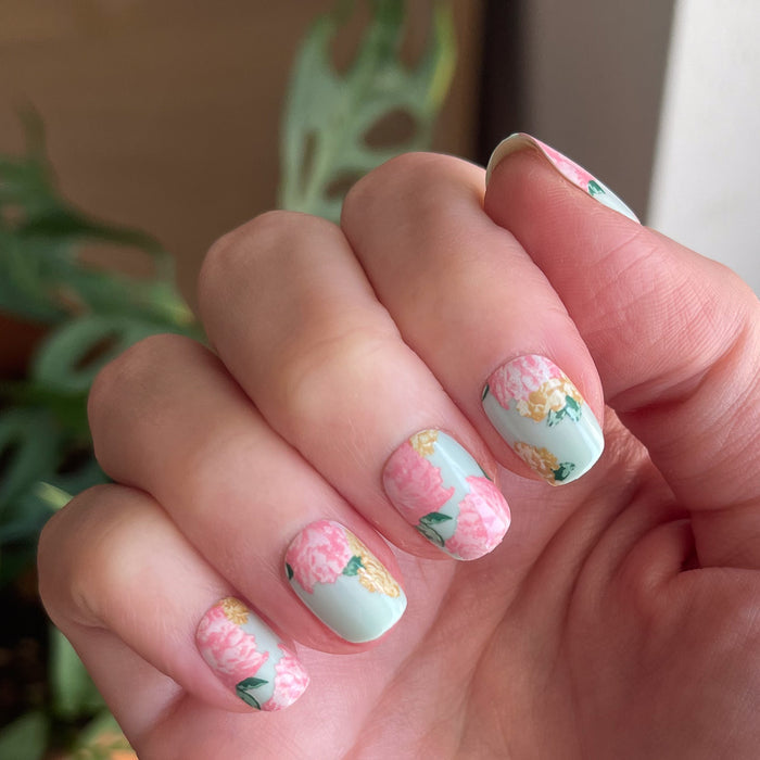 Full Floral - Press-On | Extra Short | Squoval showing floral extra short squoval press-on nails with pink and yellow flowers on hand