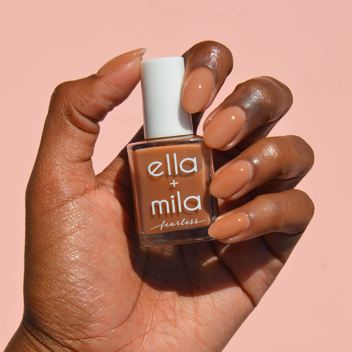 Golden Crown milky medium brown nail polish on a deep skin tone, hand holding the bottle