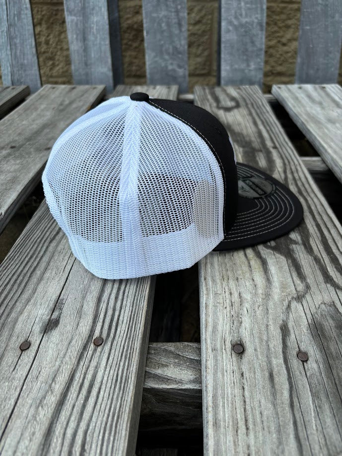 A Black and White snapback cap with a embroidered praying cowboy design on the front. Side View