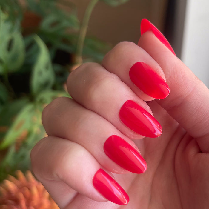 Hibiscus - Press-On | Medium | Oval showing glossy medium oval false nails in bright tropical pink on natural hand indoors
