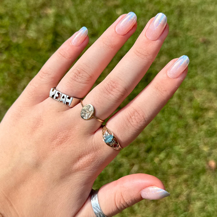 Holographic Gradient - Press-On | Short | Round nails with soft neutral base and subtle blue shimmer on hand with rings outdoors