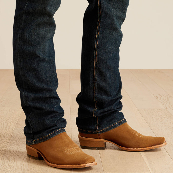 Men's Ariat M4 dark wash Pro series relaxed fit boot cut jean. Bottom view of jeans showing leg opening over boots.