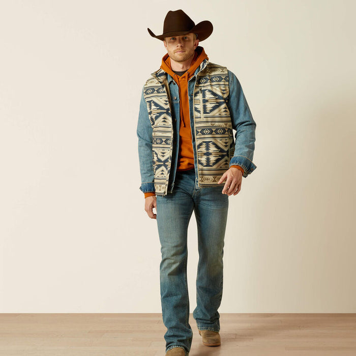 Men's Ariat aztec print weather resistant vest. Has full front zipper, standing collar, left chest vertical zippered phone pocket with an Ariat logo, slash zippered hand pockets. Hits mid hip. Full front view.