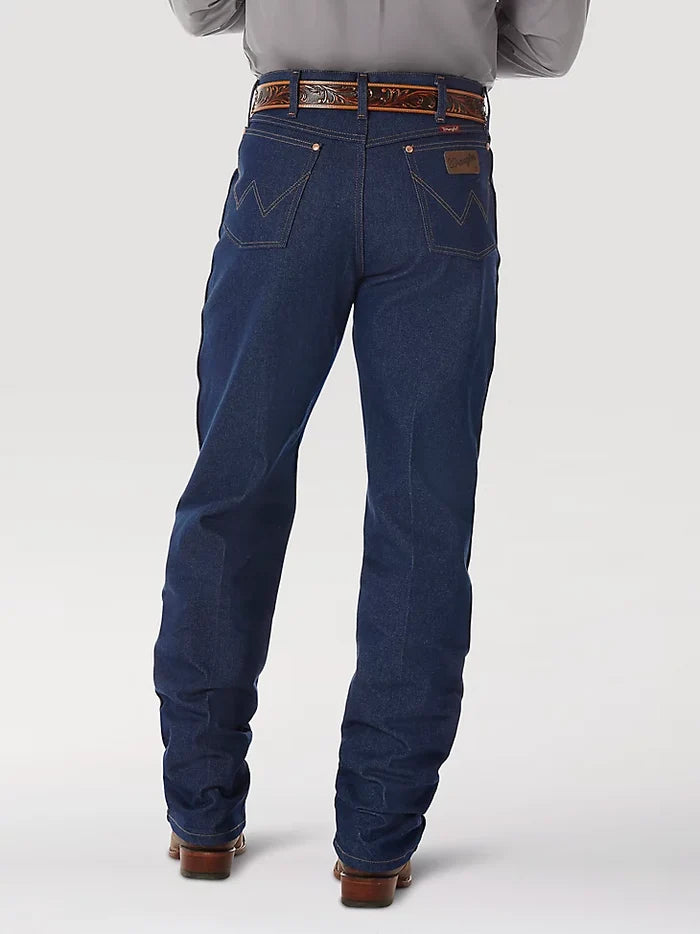A man wearing Wrangler® Cowboy Cut® relaxed fit rigid blue jeans with western shirt, belt, and boots. Back view shows patch pockets with copper rivets on top corners, "W" stitched on both, and right pocket brown neolite logo patch.