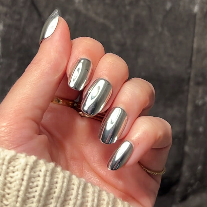 Hand displaying Mirror Chrome - Press-On | Short | Round press-on nails with shiny silver mirror finish against dark background