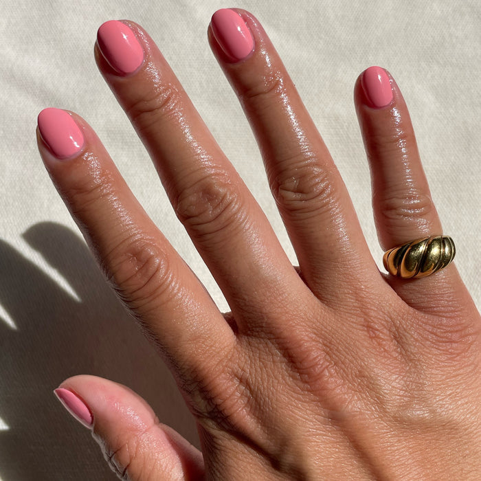 Close-up of hand with glossy nails painted in Pen Pal bright bubblegum pink long-lasting polish by Olive and June