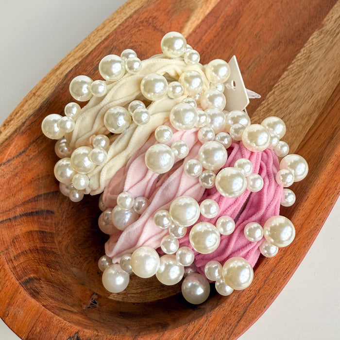 Two hair ties with pearls on a wooden surface