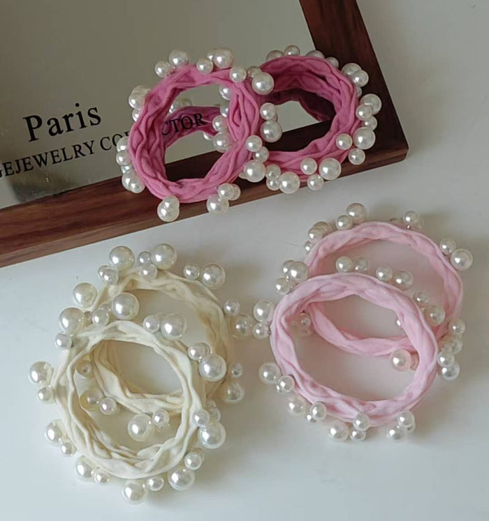 Pink and beige hair ties with pearl embellishments on a white surface.