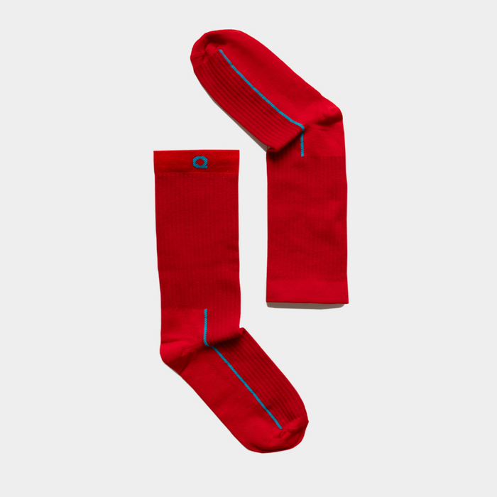 A pair of bright red socks with a small blue logo and thin blue stripe detail, displayed side by side on a plain light gray background.
