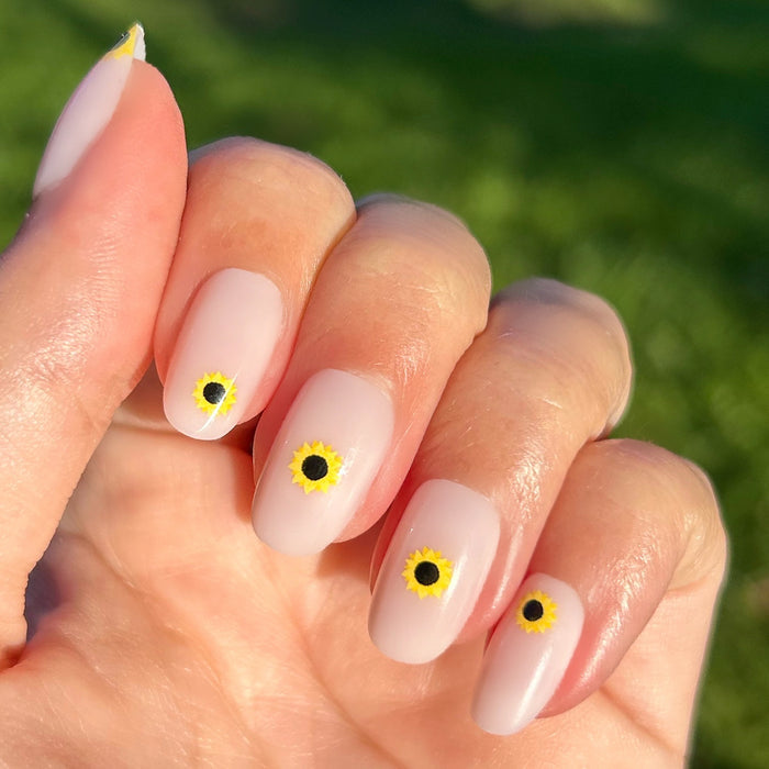 Scattered Sunflower - Press-On | Short | Round showing short round nails with single sunflower design on natural hand in sunlight outdoors