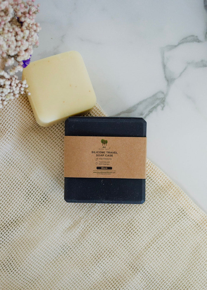 Bar of soap and packaging on a textured surface with flowers in the background