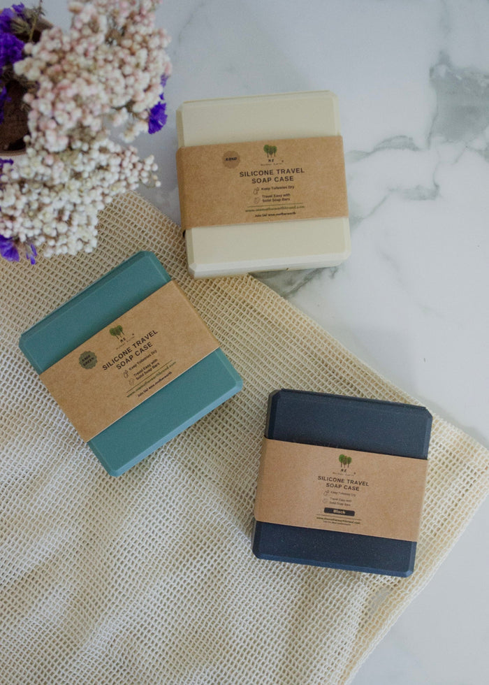 Three travel soap bars in brown packaging on a textured surface with flowers.