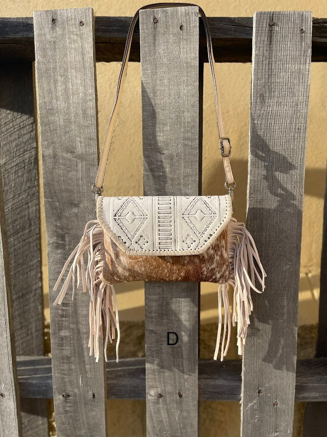 This cowhide and Beige leather bag features fringe sides and can be used as a wristlet or crossbody. It has a geometric print debossed flap with a whipstitch border.  Front View D
