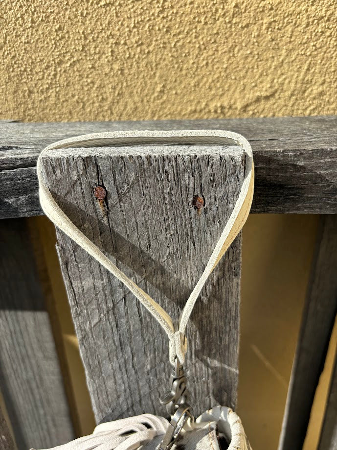 This Beige tooled leather bag can be used as a wristlet or shoulder bag with removable straps. It has side fringe and inside card slots. Close up view of wristlet strap.