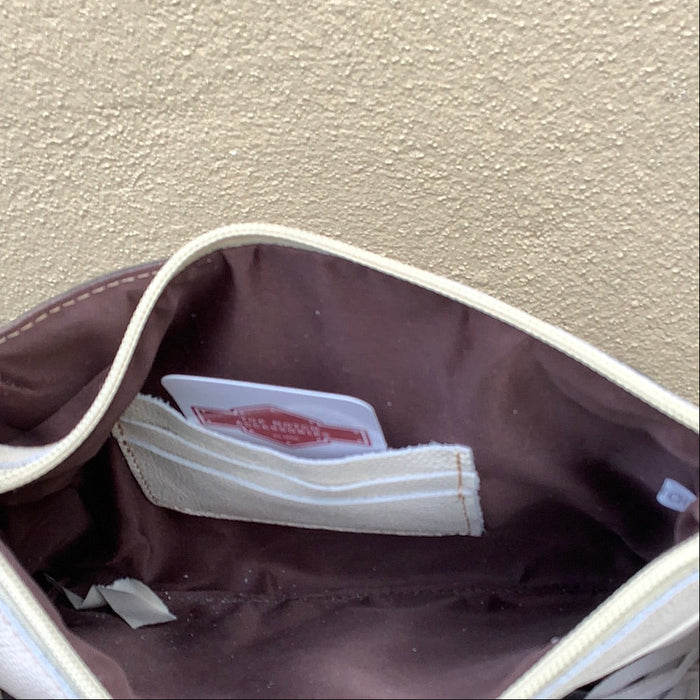 This cowhide and tooled leather crossbody bag features fringe sides and zips closed. The strap is removable and adjustable.  Inside view showing credit card slots.