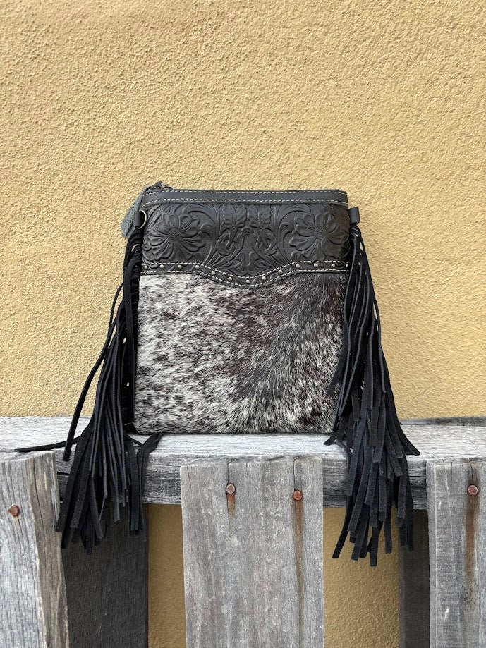 This black leather and cowhide crossbody bag has fringe details along the sides.