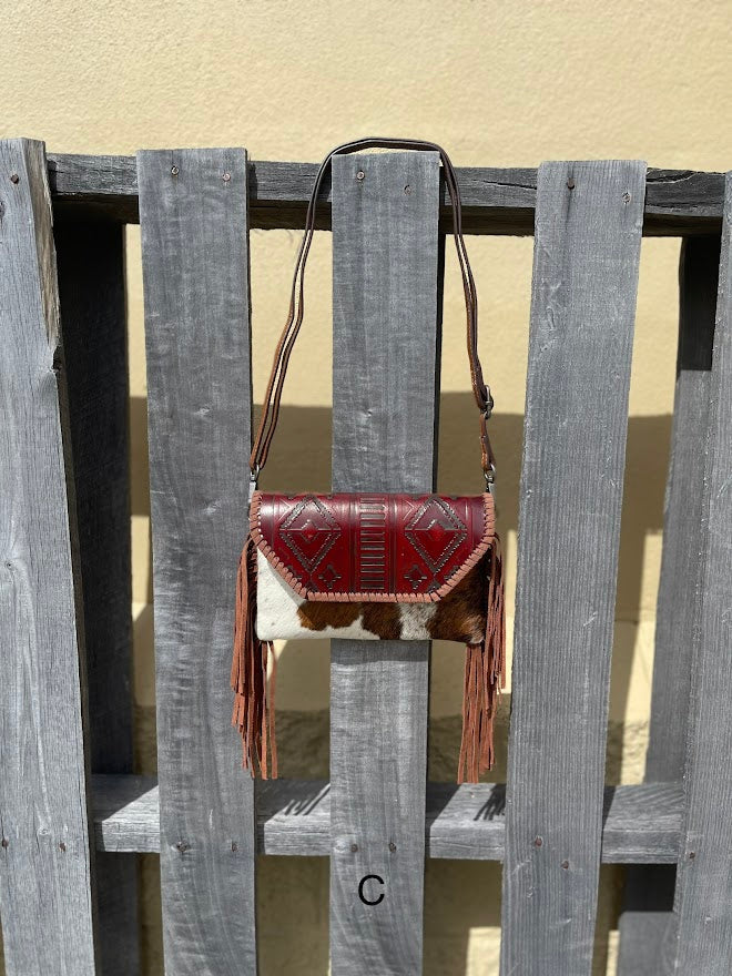 Cowhide purse with Brown leather embossed flap and tassel detail. Has a removable, adjustable shoulder strap and a wristlet strap. Front View C