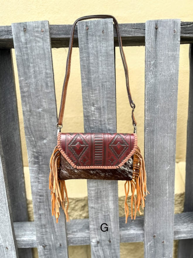 Cowhide purse with Brown leather embossed flap and tassel detail. Has a removable, adjustable shoulder strap and a wristlet strap. Front View G