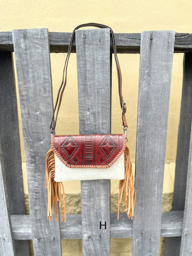 Cowhide purse with Brown leather embossed flap and tassel detail. Has a removable, adjustable shoulder strap and a wristlet strap. Front View H