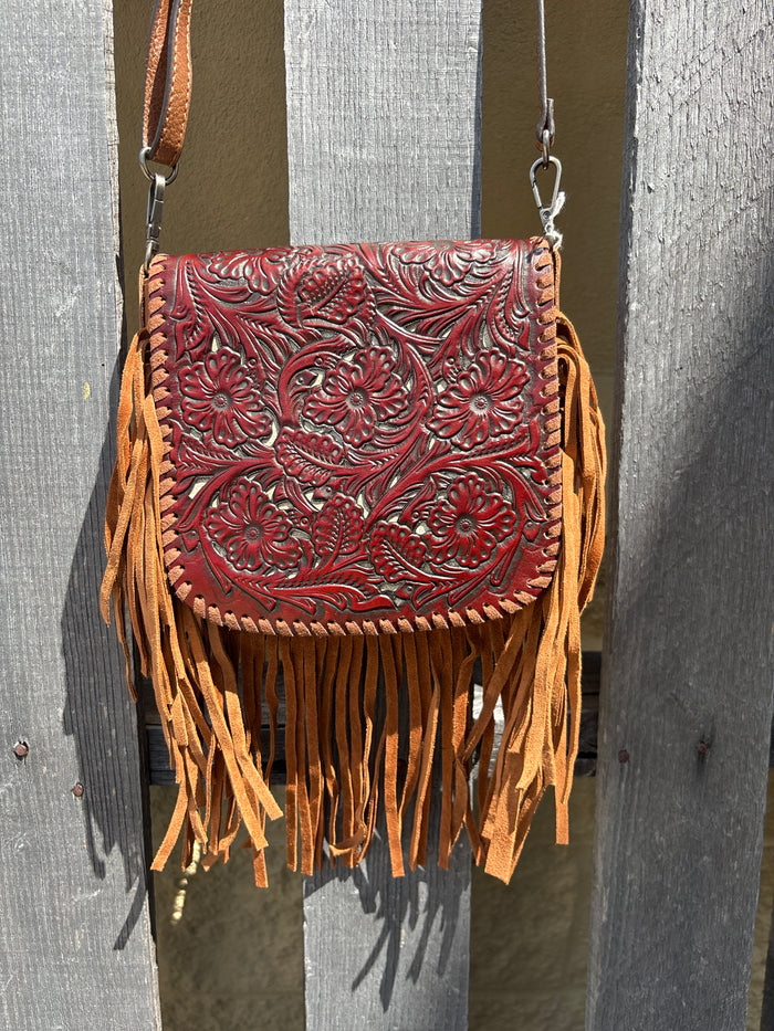 This Brown leather crossbody bag features fringe sides and a tooled flap with a whipstitch border. It has a removable and adjustable shoulder strap. Front View