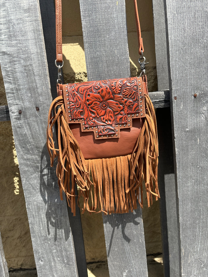 Brown leather crossbody bag with a fringe sides and a tooled design on the flap. Front View